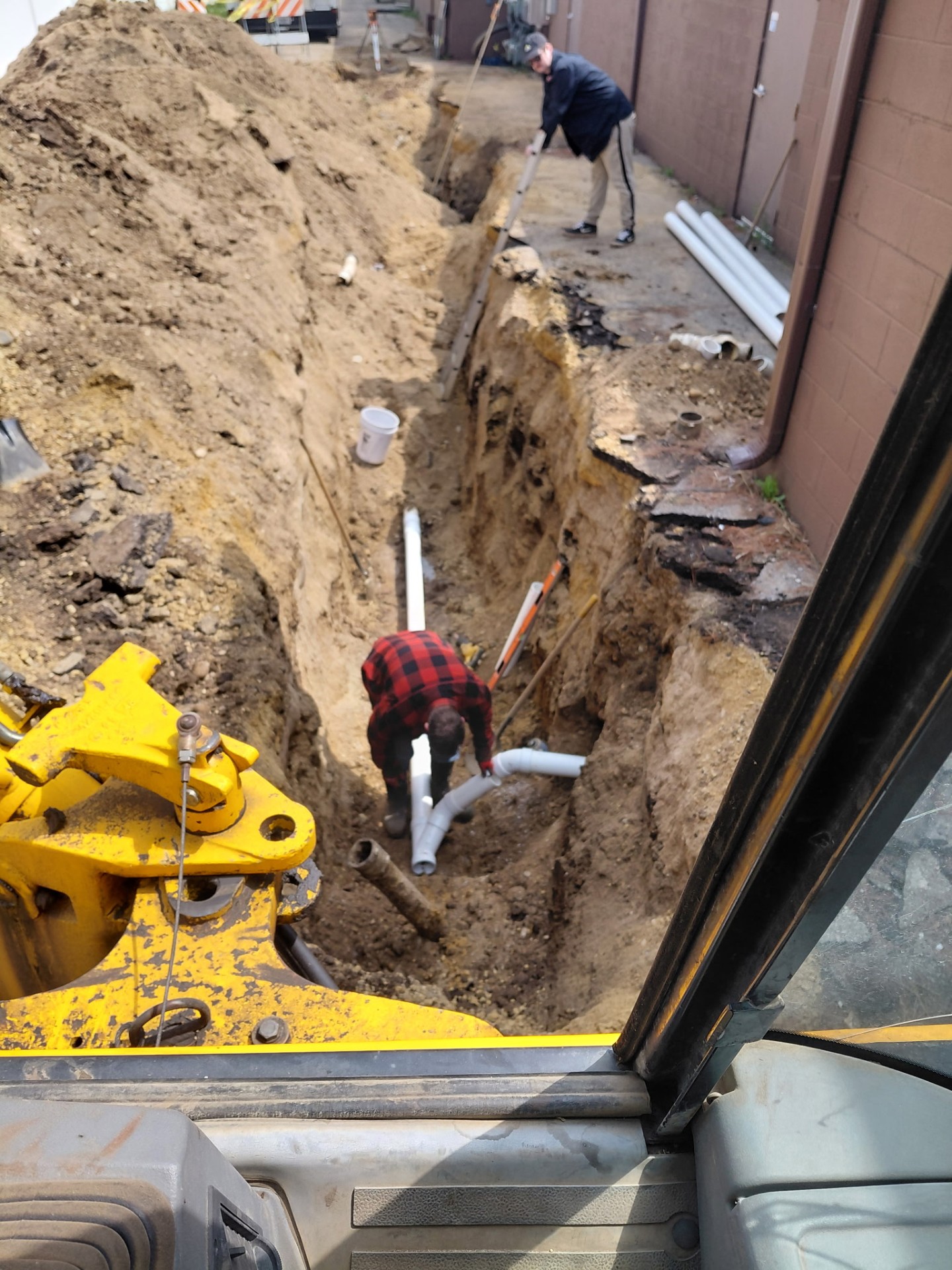 Fred Rykowski & Sons Plumbing Inc crew installing a sewer line in a deep trench